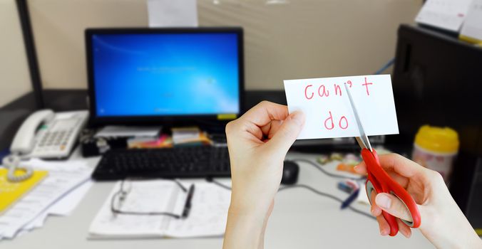 holds card with text can't do on messy desk