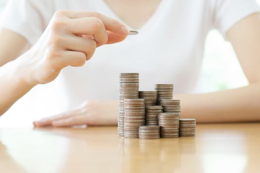 Hand put coins to stack of coins on white background