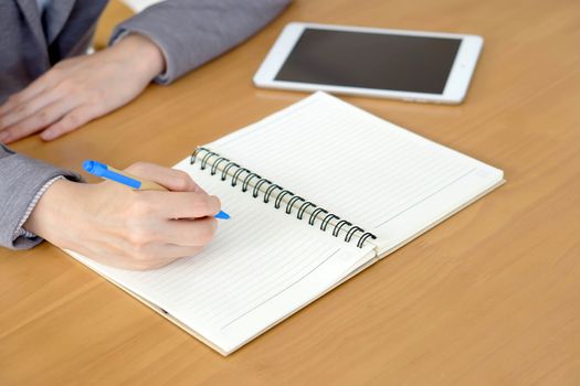 Woman hands with tablet PC and notepad at office