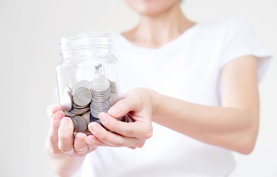 Woman holding money jar with coins close up