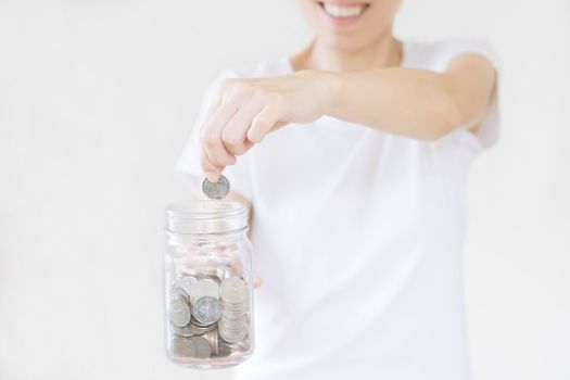 business, finance, saving, banking and people concept - close up of woman hands putting us dollar money into glass mason jar