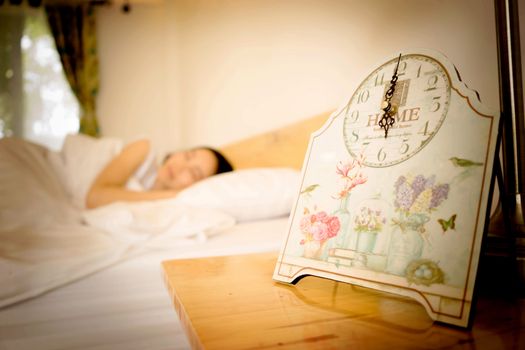 Young woman sleeping in bed with alarm at night