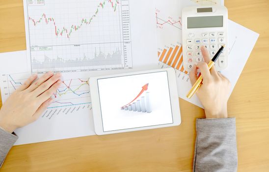 Close-up Of Businesswoman Holding Digital Tablet With Graphs On Desk