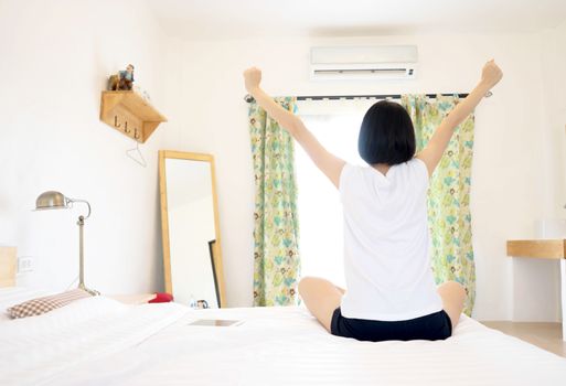 Woman stretching in her bed, rear view