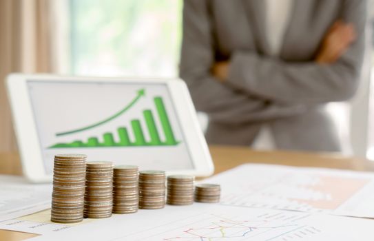 Grow up coins stack with business and finance graph screen on laptop computer on desk of investor adviser. Businesswomen background 