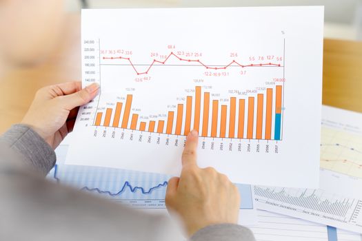 Businesswoman hands over paper and financial chart 
