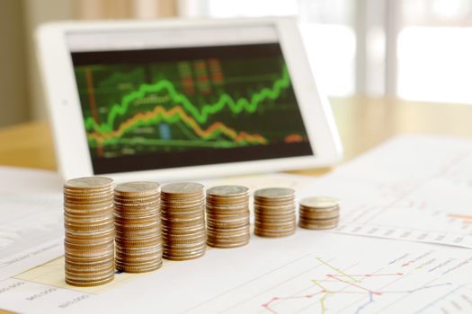 Grow up coins stack with business and finance graph screen on laptop computer on desk of investor adviser. Concept of financial and investment growth.