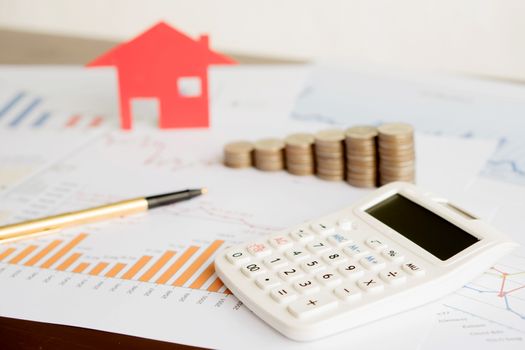  With House Model And Stack Of Coins On Desk