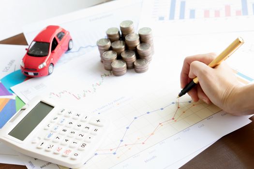 Hand hold a pen and press calculator and toy car and coins and business chart with sun lights color tone backgrounds