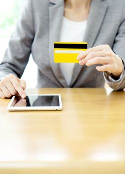 Close-up woman's hands holding a credit card and using tablet pc 