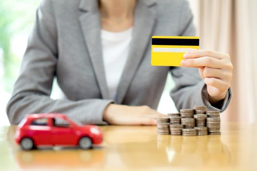Businesswoman hand hold credit card, a toy car and a stack of coins