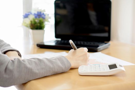 young woman writes a text message on paper and laptop,calculator