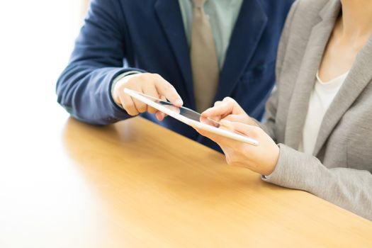 Two confident businesspeople using a digital tablet together while working at a table