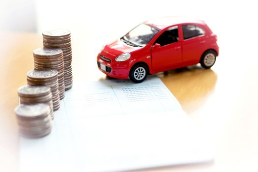 Coins stack in columns on saving book and car on finance concept