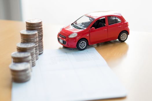 Row of coins on account book and car on finance concept