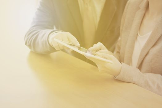 Two confident businesspeople using a digital tablet together while working at a table