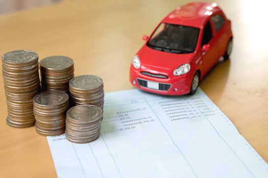 Row of coins on account book and car on finance concept