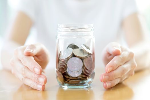 Woman holding money jar with coins close up