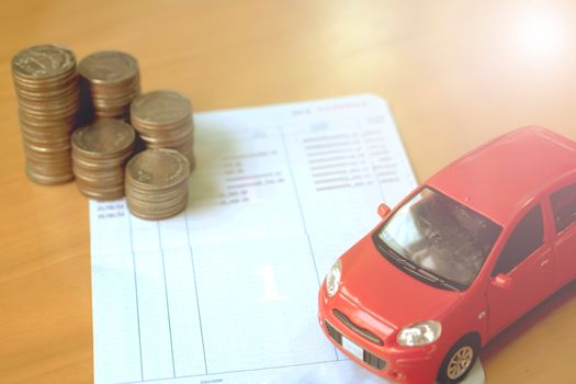 Row of coins on account book and car on finance concept