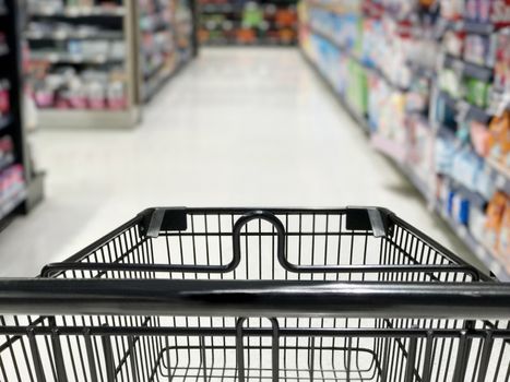 Shopping cart with wine bottles shelves in supermarket