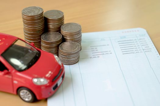 Row of coins on account book and car on finance concept