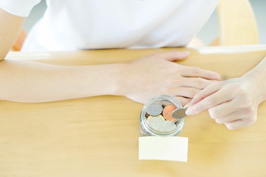 Woman hands with coins in glass jar, top view