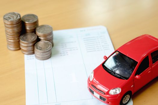 Row of coins on account book and car on finance concept