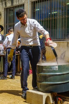 Haifa, Israel - April 16, 2019: Ultra-orthodox Jews perform Hagalah as part of preparation for Passover. By immersing utensils in boiling water (and some by fire) they become kosher or purified