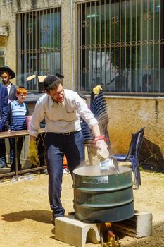 Haifa, Israel - April 16, 2019: Ultra-orthodox Jews perform Hagalah as part of preparation for Passover. By immersing utensils in boiling water (and some by fire) they become kosher or purified