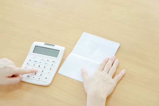 Businesswoman use calculator beside passbook 