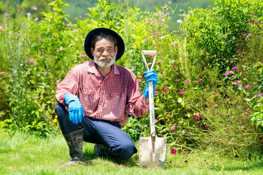 Old man working with shovel in backyard garden.