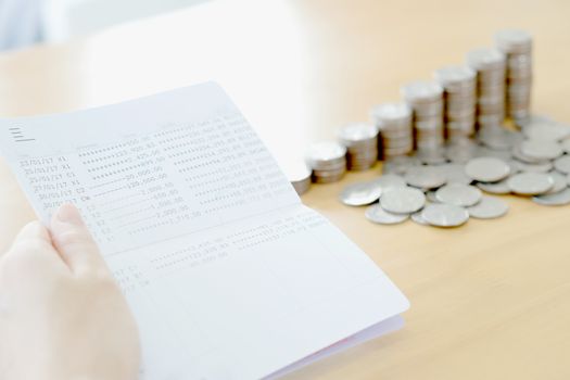 Woman hold passbook on hand, coins background