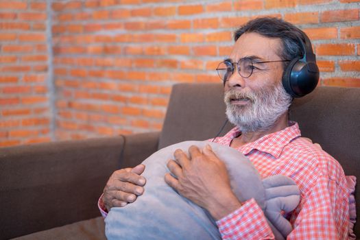 The old man listens to the music from the headphones,Enjoying the rich sound of the music.
