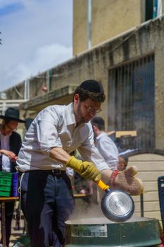 Haifa, Israel - April 16, 2019: Ultra-orthodox Jews perform Hagalah as part of preparation for Passover. By immersing utensils in boiling water (and some by fire) they become kosher or purified