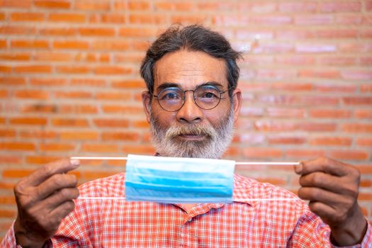 Portrait of smiling senior man ready to wearing protective mask to Protect Against Covid-19,Concept of recommendations for protection against the virus.