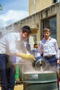 Haifa, Israel - April 16, 2019: Ultra-orthodox Jews perform Hagalah as part of preparation for Passover. By immersing utensils in boiling water (and some by fire) they become kosher or purified