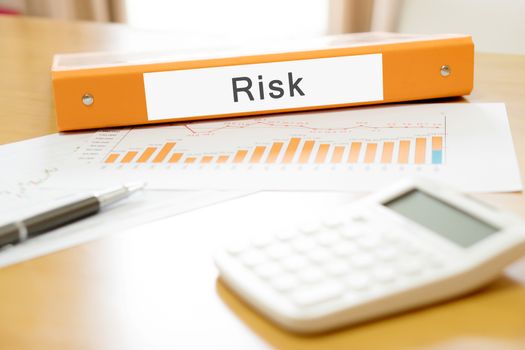 Orange  binder debtor on desk in the office with calculator and pen