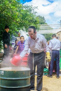 Haifa, Israel - April 16, 2019: Ultra-orthodox Jews perform Hagalah as part of preparation for Passover. By immersing utensils in boiling water (and some by fire) they become kosher or purified