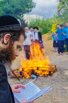 Haifa, Israel - April 19, 2019: Jewish man read a blessing, part of a Biur (burning) Chametz (leavened foods) ceremony, in Haifa, Israel. This is part of the Passover holiday traditions