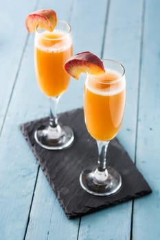 Bellini champagne cocktail in crystal glass on blue wooden table
