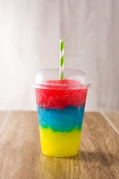 Colorful slushie of different flavors with straw in plastic cup isolated on white background.