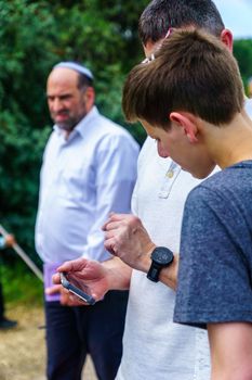 Haifa, Israel - April 19, 2019: Jewish man use a smartphone to read a blessing, part of a Biur (burning) Chametz (leavened foods) ceremony. This is part of the Passover holiday traditions