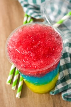 Colorful slushie of differents flavors with straw in plastic cup