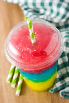 Colorful slushie of differents flavors with straw in plastic cup