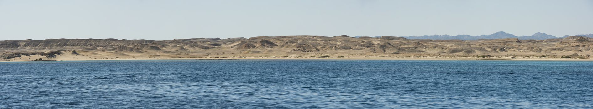 Panoramic view of a rocky remote desert coastline from tropical ocean
