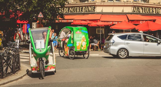 PARIS, FRANCE - July 11, 2017 : bicycle taxis drivers wait for customers in front of the terrace of a restaurant on a summer day