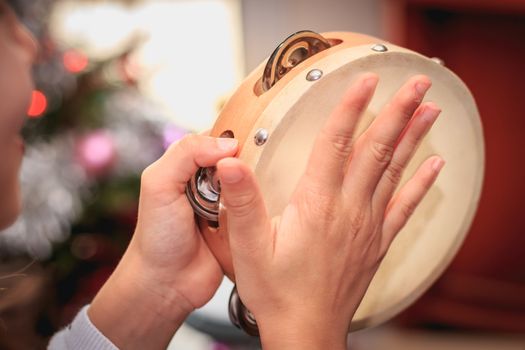 little girl is playing the tambourine in front of a Christmas tree