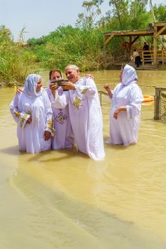 Qasr el Yahud, West Bank - April 24, 2019: Pilgrims baptize in Qasr el Yahud (Castle of the Jews), in the Jordan River. It is the traditional site of the baptism of Jesus by John the Baptist