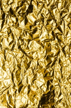 Crumpled gold metal foil with ambient reflection