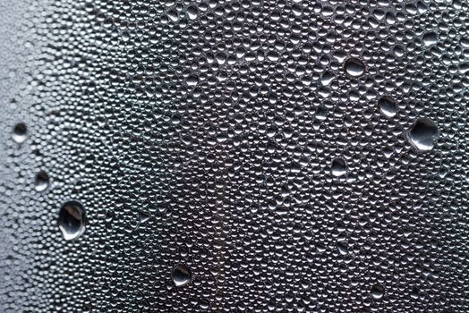 Many little water drops due to condensation on a plastic bottle curved surface